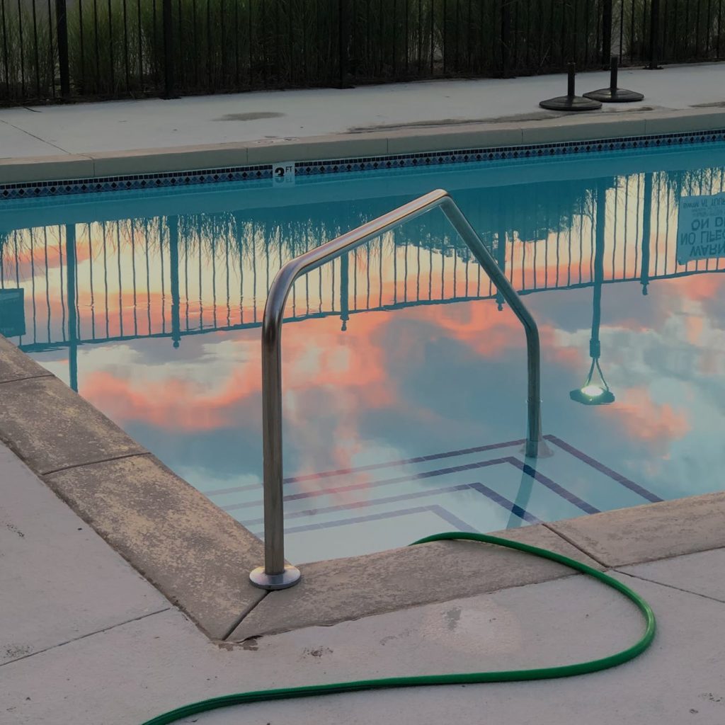 pool with railing near hose and fence in hotel yard